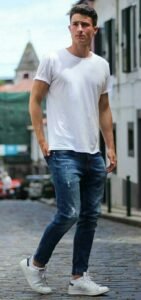 Man in casual white t-shirt and jeans outfit walking